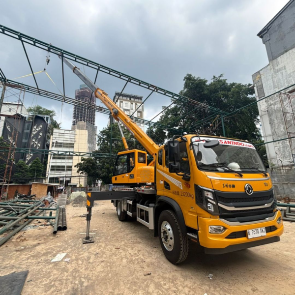 Unit XCMG XCT8 PT Asanindo mengangkat rangka baja untuk proyek konstruksi gedung bertingkat di kawasan Cakung Jakarta Timur — lifting presisi di area sempit perkotaan